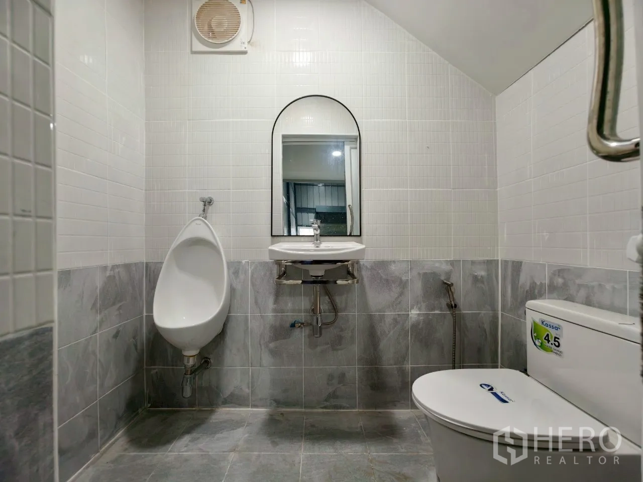 Warehouse for rent in Phra Khanong, Bangkok - Clean tiled restroom with toilet, urinal, sink, and ventilation fan.