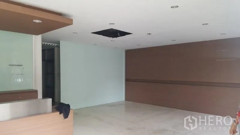 Warehouse for rent in Suan Luang, Bangkok - Ground-floor reception or showroom with built-in counter, drop ceiling and glass feature wall.