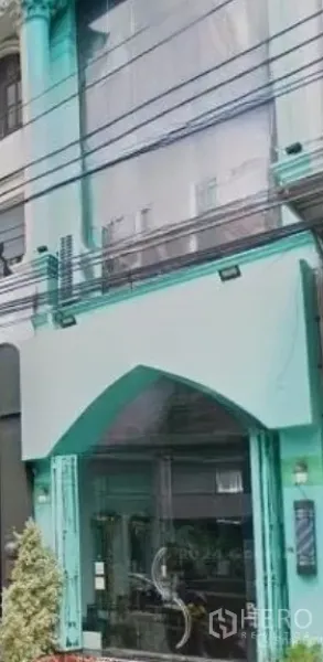 店屋 出租在Watthana, Bangkok - 瓦他那区临街商铺外立面，薄荷绿色墙体、拱形入口与大面积玻璃门窗，近BTS Thong Lo站。