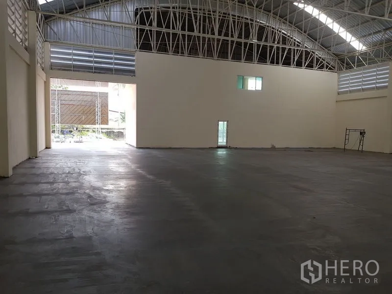 Factory for rent or sale in Mueang Samut Prakan, Samut Prakan - Open warehouse space with a wide loading entrance and natural light panels.
