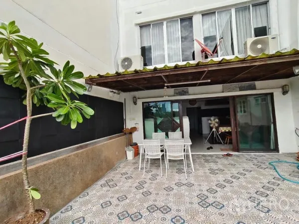 Townhouse for rent or sale in Bang Kho Laem, Bangkok - Ground-floor patio with patterned tiles, dining set, sliding glass doors and awning at a Bangkok townhouse.