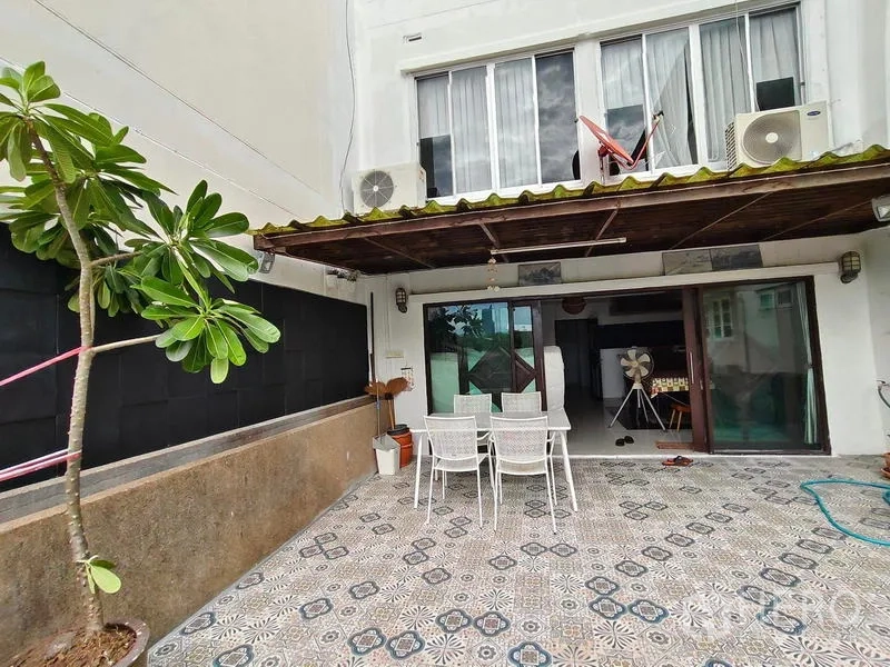 Townhouse for rent or sale in Bang Kho Laem, Bangkok - Ground-floor patio with patterned tiles, dining set, sliding glass doors and awning at a Bangkok townhouse.