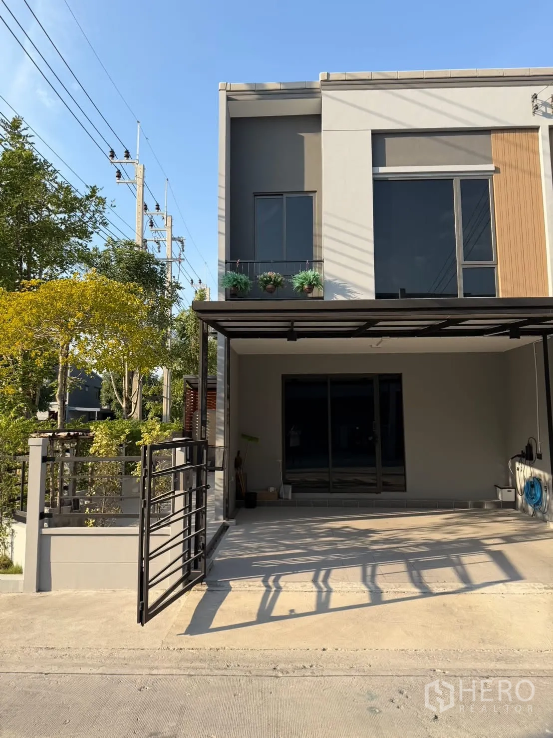 Townhouse for rent in Bang Phli, Samut Prakan - Modern townhouse façade with gated covered carport and small balcony planters.