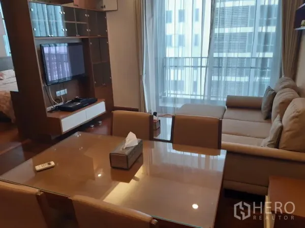 คอนโด ให้เช่าในWatthana, Bangkok - ส่วนรับประทานอาหารเชื่อมสู่ห้องนั่งเล่น ทีวีติดผนัง พร้อมประตูกระจกบานเลื่อนออกไประเบียง