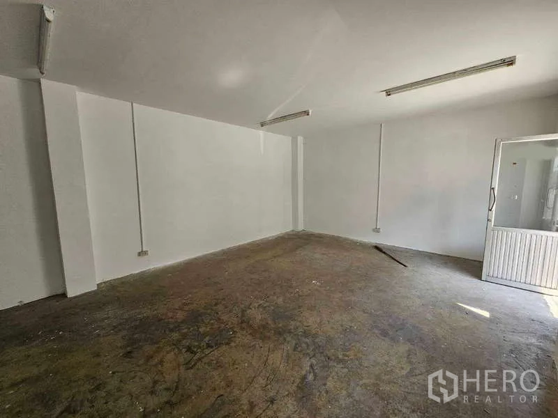Warehouse for rent in Bang Bua Thong, Nonthaburi - Simple ground-floor office room with white walls, fluorescent lighting, and a windowed door.