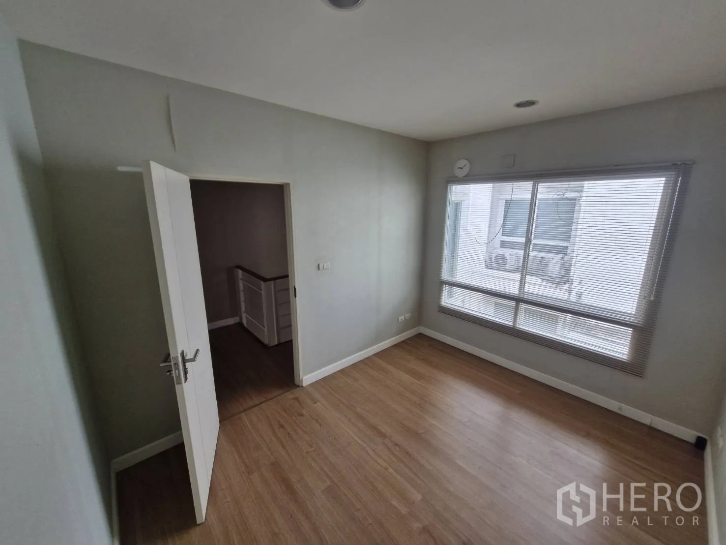 Townhouse for sale in Rat Burana, Bangkok - Sunlit bedroom with large window blinds and wood-style flooring.