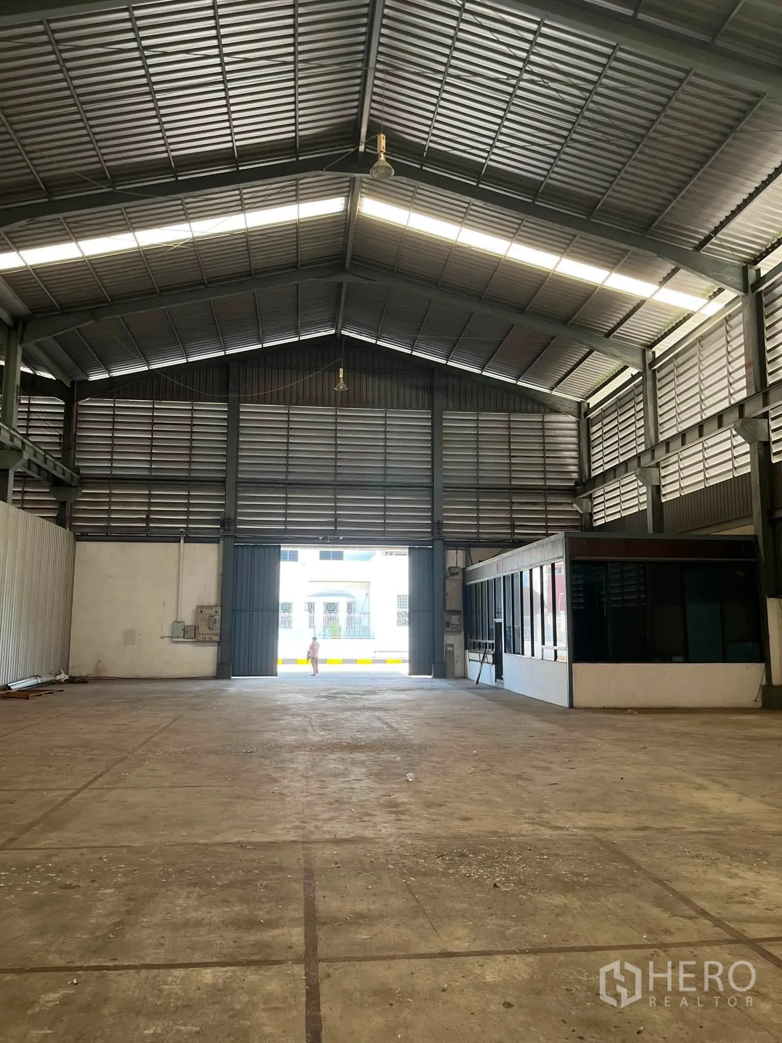 Warehouse for rent in Bang Phli, Samut Prakan - Spacious warehouse interior with high metal roof, large sliding doors, and a glass-partitioned office.