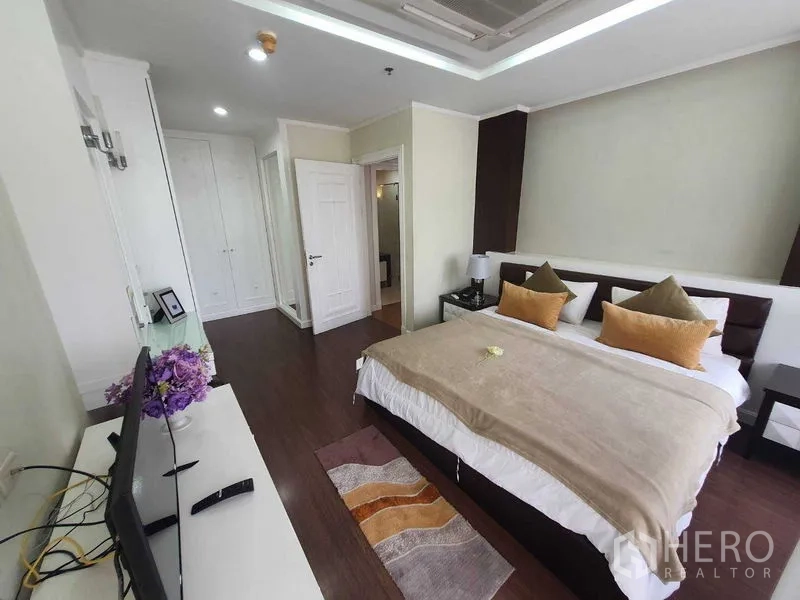 房间 出租在Watthana, Bangkok - 主卧配特大床、衣柜与电视柜，深色木地板