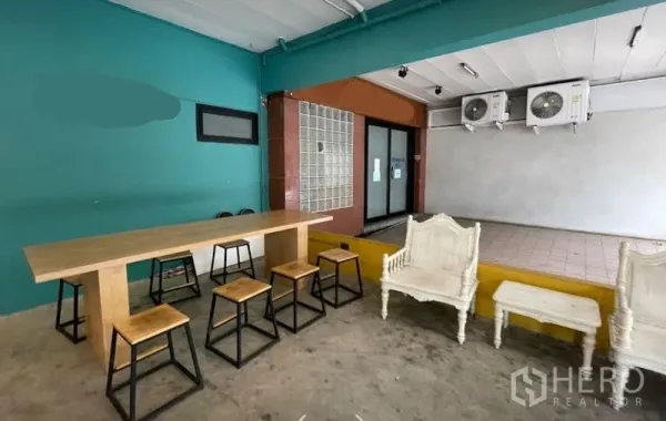 Retail Space for rent in Watthana, Bangkok - Ground-floor retail area with long wooden table, stools, raised platform and wall-mounted air conditioners.