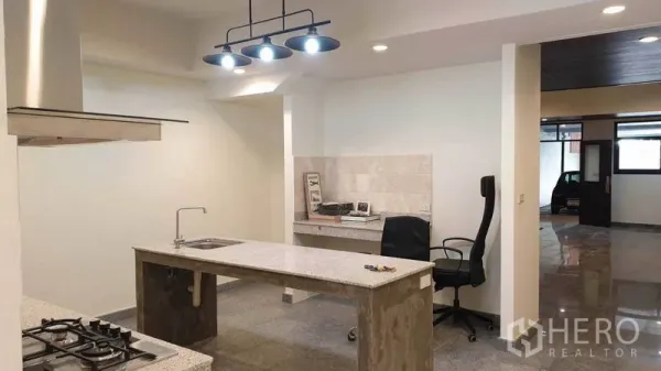 Townhouse for rent or sale in Khlong Toei, Bangkok - Open-plan kitchen with pendant lights, stone island and a built-in workspace.