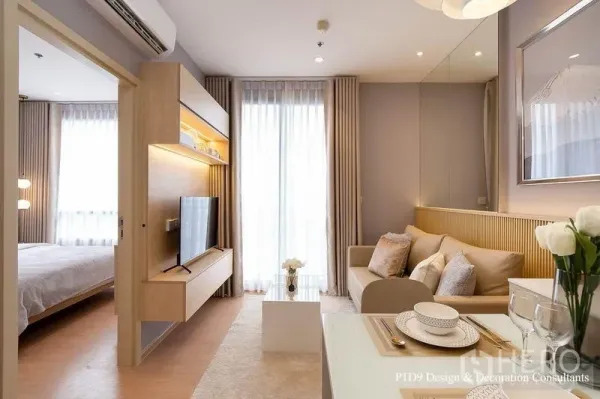 Condominium for rent in Watthana, Bangkok - Living room with TV console and shelving, sliding door to bedroom and full‑height windows to the balcony.