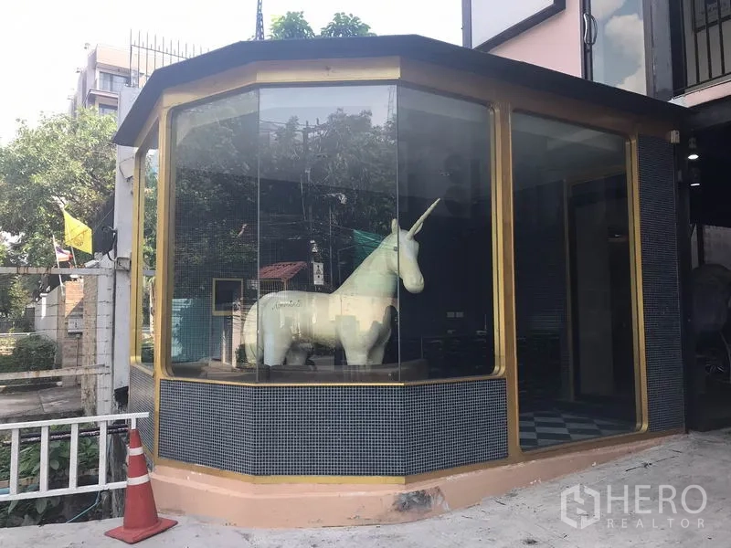 零售空间 出租在Watthana, Bangkok - 转角落地玻璃店面与金色边框的零售门脸，曝光度高。
