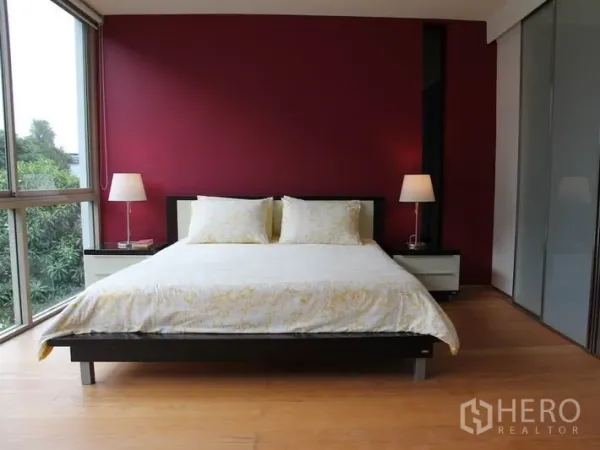 คอนโด ให้เช่าในKhlong Toei, Bangkok - ห้องนอนใหญ่ผนังแต่งสีแดง มุมกระจก และโคมไฟหัวเตียง.