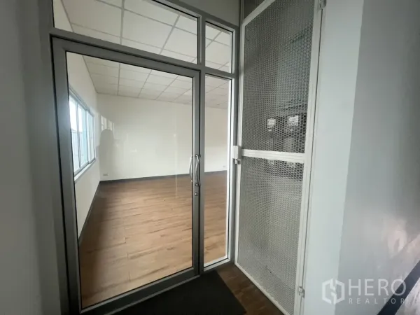 零售空间 出租 - 带安全格栅的玻璃入口，通向采光充足的木地板零售空间。