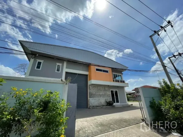 Warehouse for rent in Bang Kapi, Bangkok - Street-side view of the gated warehouse exterior with power lines and a bright sky.