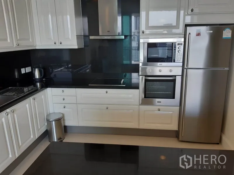 คอนโด ให้เช่าในWatthana, Bangkok - ครัวรูปตัวแอลสมัยใหม่ ตู้สีขาว เคาน์เตอร์หินสีดำ และเครื่องใช้สแตนเลส