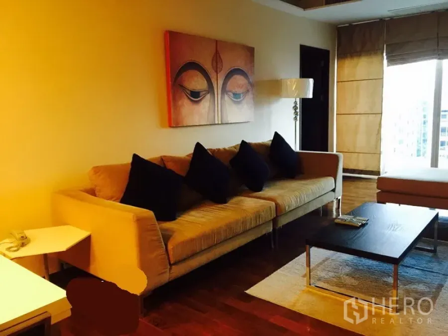 Condominium for rent in Watthana, Bangkok - Cozy lounge with long sofa, wall art above, coffee table, and a large window offering city views.