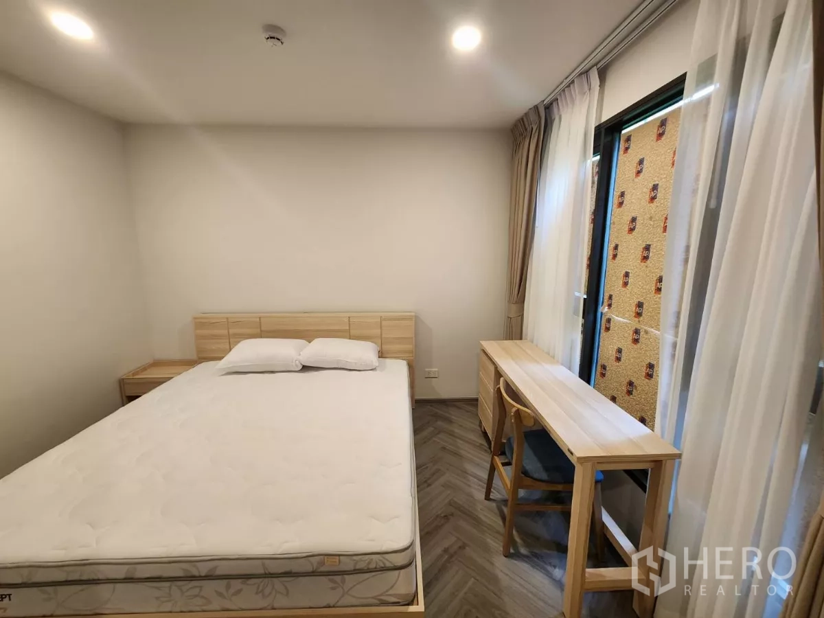 Townhouse for rent in Khlong Toei, Bangkok - Second bedroom with bed, long study desk and large windows.