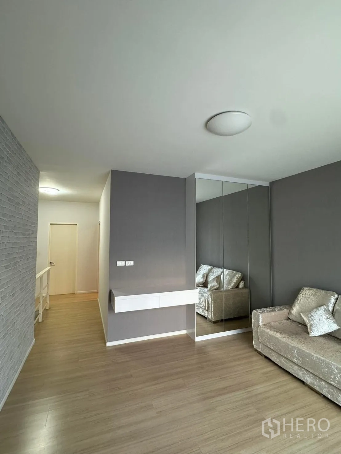 联排别墅 for rent in Suan Luang, Bangkok - 楼上一处起居区，悬空层板、镜面柜与灰色强调墙。