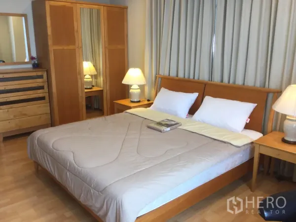 คอนโด ให้เช่าในKhlong Toei, Bangkok - ห้องนอนใหญ่ เตียงคิงไซส์ โคมไฟหัวเตียง และตู้เสื้อผ้าไม้เข้าชุด