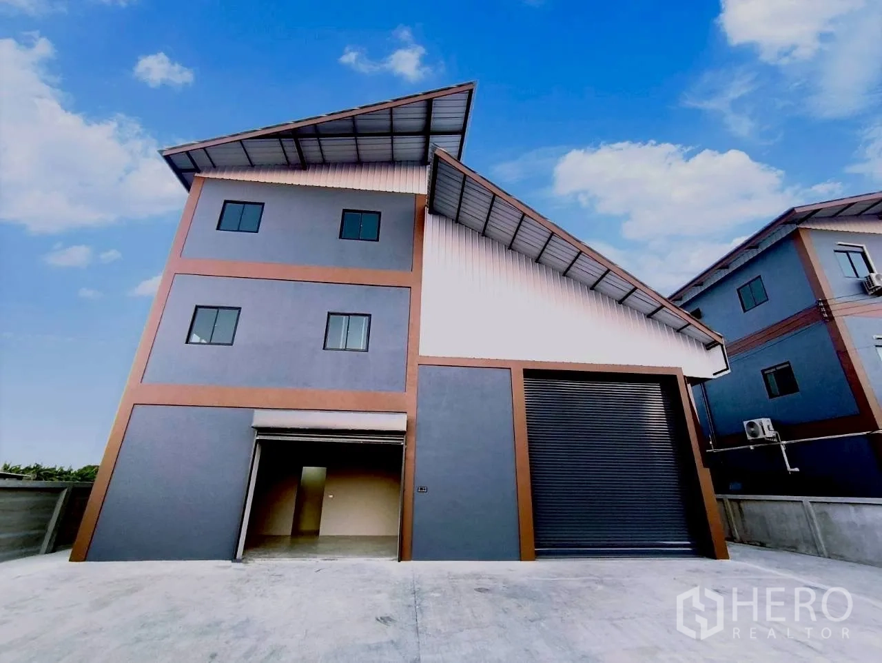 仓库 for rent in Mueang Nonthaburi, Nonthaburi - 仓库正面，可见两扇卷帘门与出入口车道。