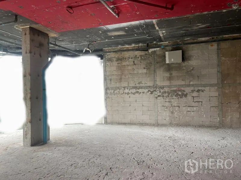 零售空间 出租在Watthana, Bangkok - 壳体零售室内，裸露红色顶棚、混凝土柱与砌块墙，待装修。