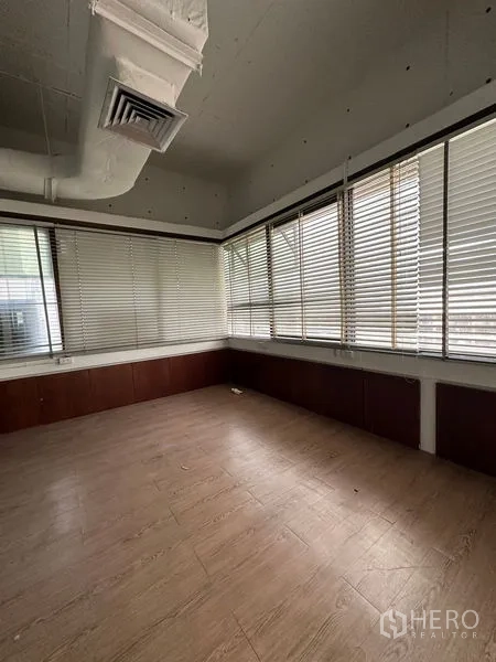 Office Space for rent in Watthana, Bangkok - Corner office with wood floors, wraparound windows, and venetian blinds for light control.