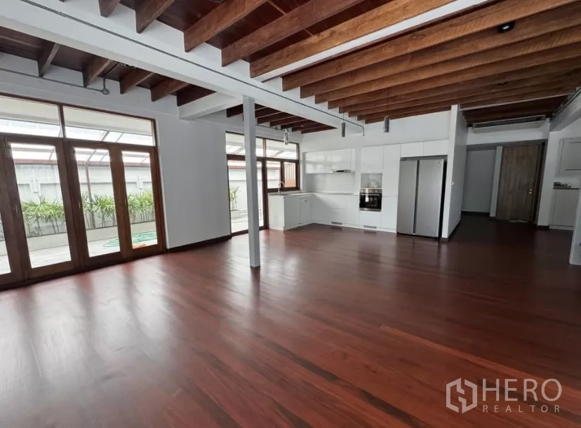 独立式住宅 出租在Watthana, Bangkok - 开放式客餐厅，外露木梁与整片实木地板。