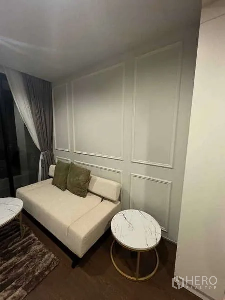 คอนโด ให้เช่าในKhlong Toei, Bangkok - พื้นที่นั่งเล่นกะทัดรัด โซฟาสีครีม ผนังตกแต่งบัว และโต๊ะข้างทรงกลม