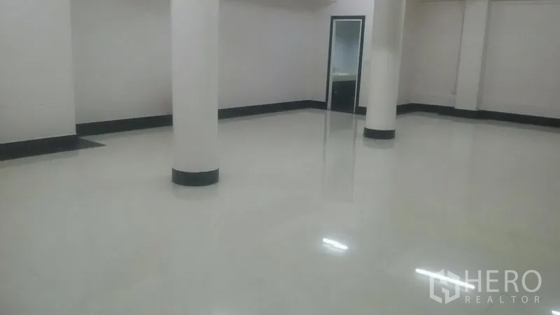 Office Space for rent in Sathon, Bangkok - Large empty office room with columns and a doorway to a wash area, glossy tiled flooring.