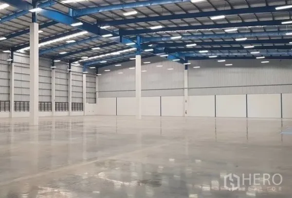 货栈 出租在Samut Prakan - 开放式仓库区域，白色立柱、反光地坪与金属屋顶板。