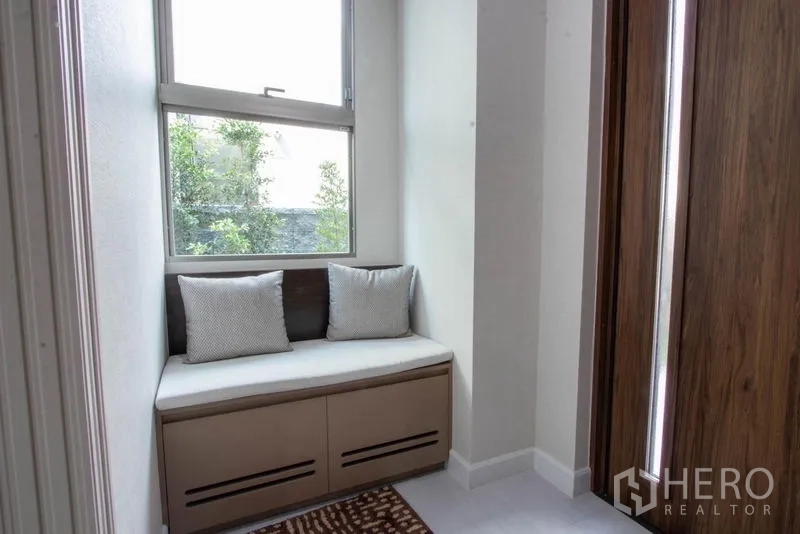 Detached House for sale in Saphan Sung, Bangkok - Cozy window seat with storage bench and abundant natural light beside a wooden door.