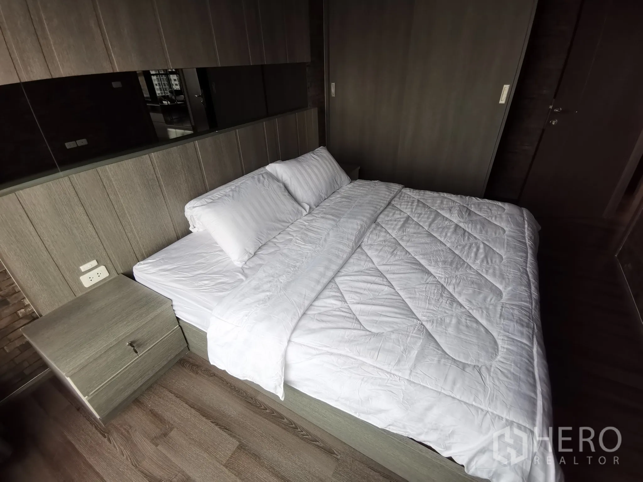 公寓 出租或出售在Watthana, Bangkok - 主卧配大床、床头柜与木质装饰墙。