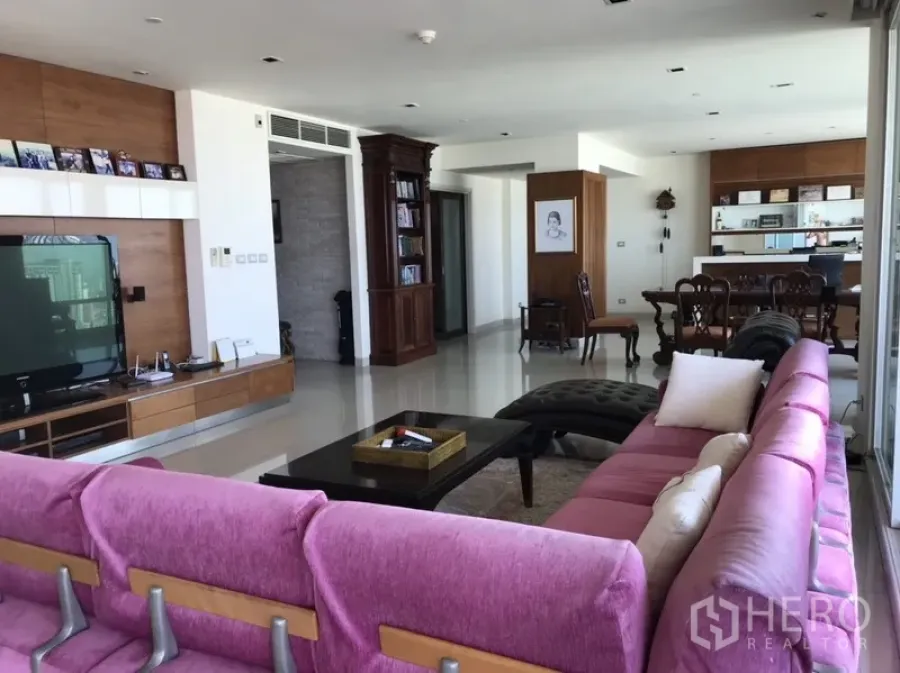 คอนโด ให้เช่าหรือขายในKhlong San, Bangkok - ห้องนั่งเล่นและรับประทานอาหารแบบโอเพ่นพร้อมโซฟาสีชมพู ผนังทีวีไม้ และหน้าต่างวิวเมือง