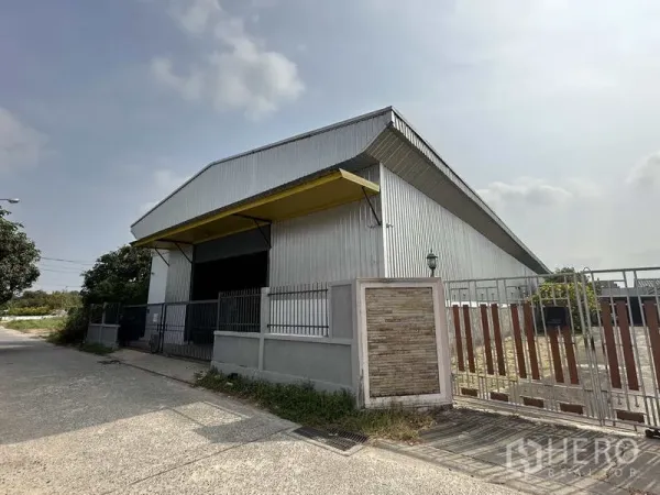 货栈 出租在Bang Khen, Bangkok - 邦肯区金属外墙仓库外观，黄色卸货雨棚与安全大门，临安静街道。