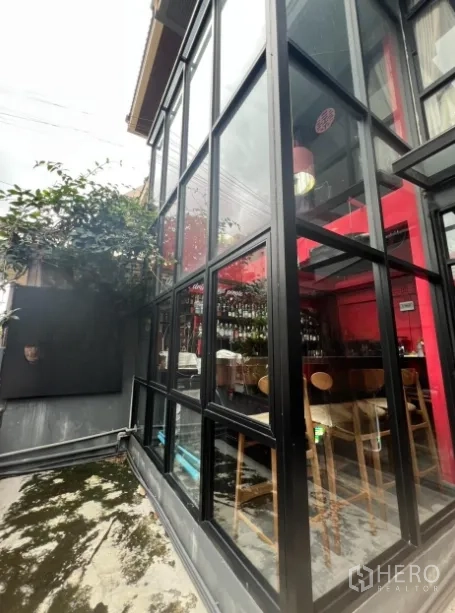 零售空间 出租在Watthana, Bangkok - 侧面落地玻璃，可见吧台座位与红色室内设计。