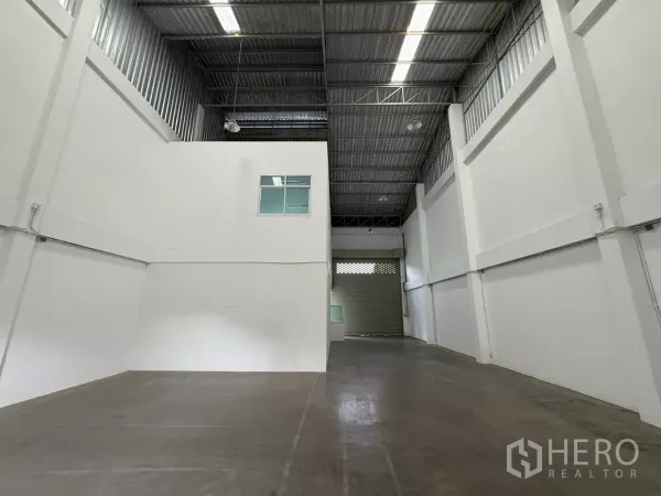 Factory for rent in Phra Samut Chedi, Samut Prakan - Spacious production bay facing a large roller shutter door.