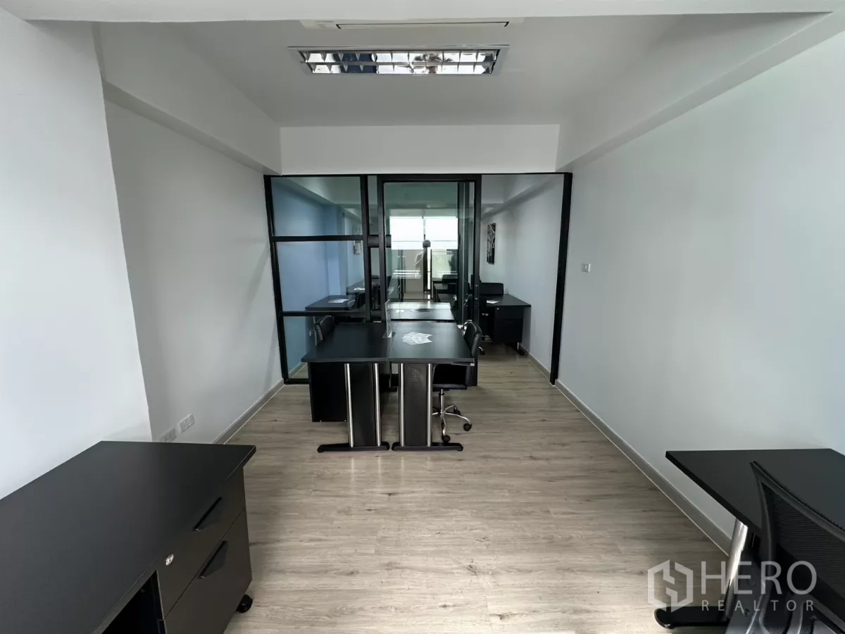 Office Space for rent in Watthana, Bangkok - Long workspace corridor featuring multiple desks, fluorescent lighting and modern minimalist finishes.
