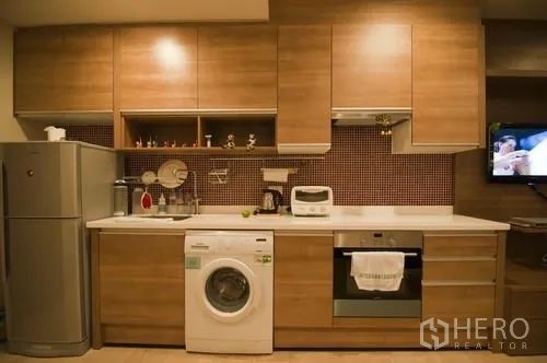 公寓 出租在Khlong Toei, Bangkok - 开放式厨房，木质橱柜、冰箱、烤箱、灶台与室内洗衣机一应俱全。