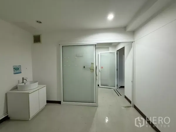 办公空间 出租在Din Daeng, Bangkok - 走廊式工作区，磨砂玻璃门、白色柜体与明亮照明。