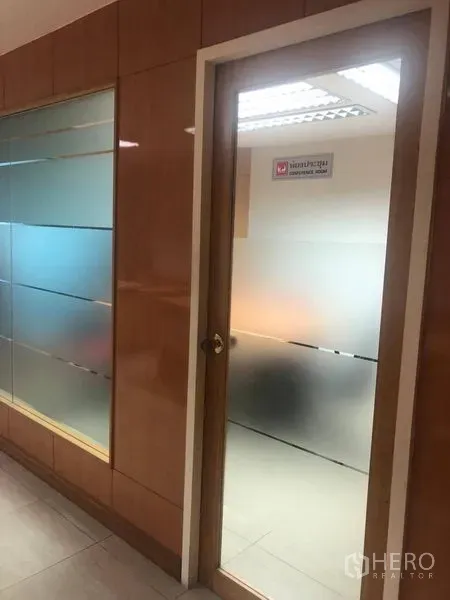 办公空间 出租在Sathon, Bangkok - 走廊旁的磨砂玻璃门与玻璃隔墙，木质墙面装饰的办公区。