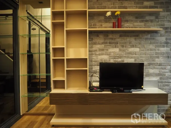 Condominium for rent in Phaya Thai, Bangkok - Living area media wall with built-in shelves, TV console and a brick accent wall.