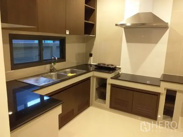 Detached House for rent or sale in Bang Kapi, Bangkok - Separate L-shaped kitchen with black countertops, double sink and stainless range hood.