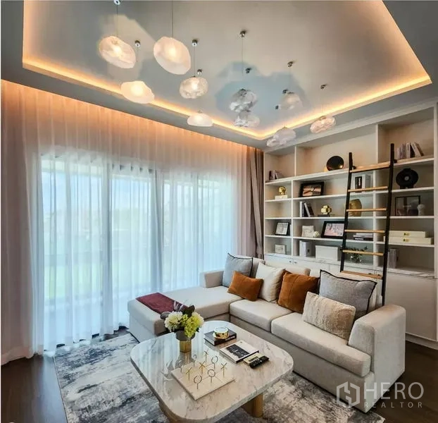 Detached House for sale in Bang Phli, Samut Prakan - Family room with sectional sofa, built-in bookshelf and sliding glass doors.