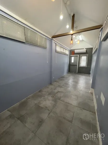 พื้นที่ขายปลีก ให้เช่า - ภายในร้านเพดานจั่ว คานเหล็ก ไฟแขวนหลายดวง และแอร์ที่ด้านหลัง