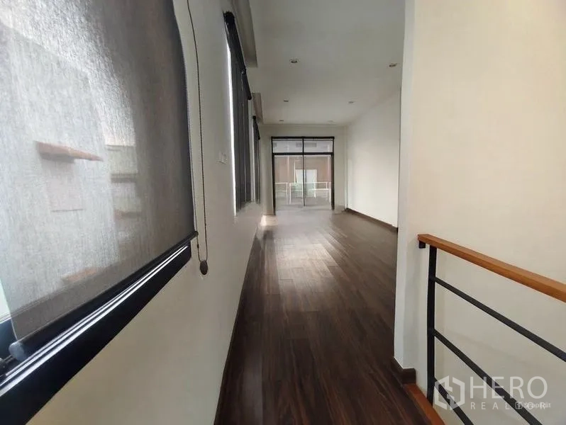 Shophouse for rent or sale in Pom Prap Sattru Phai, Bangkok - Upper-floor hallway with wood floors and windows leading toward a front room.