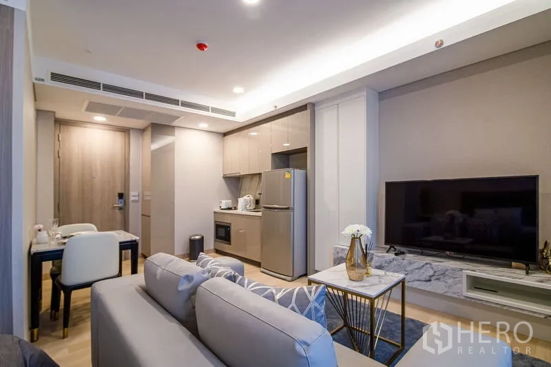 คอนโด ให้เช่าในKhlong Toei, Bangkok - มุมนั่งเล่นอบอุ่น ทีวีบนชั้นหินอ่อน มองไปยังครัวและโต๊ะทานอาหาร