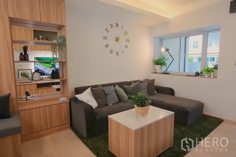 ทาวน์เฮาส์ ให้เช่าในPrawet, Bangkok - ห้องนั่งเล่นอบอุ่น โซฟาเข้ามุม นาฬิกาติดผนัง และชั้นไม้