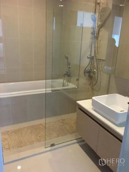 Condominium for rent in Ratchathewi, Bangkok - Contemporary bathroom with glass shower, bathtub and vanity basin.