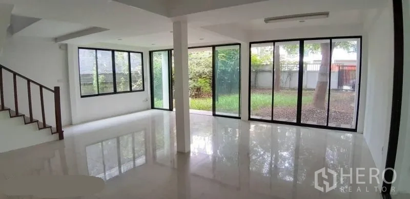 Detached House for rent in Prawet, Bangkok - Corner living room with floor-to-ceiling windows opening to a private green garden.